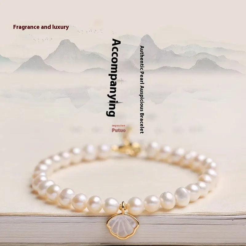 Women's freshwater pearl bracelet with a fan-shaped shell on a wrist, showing elastic and extension chain fastening options.