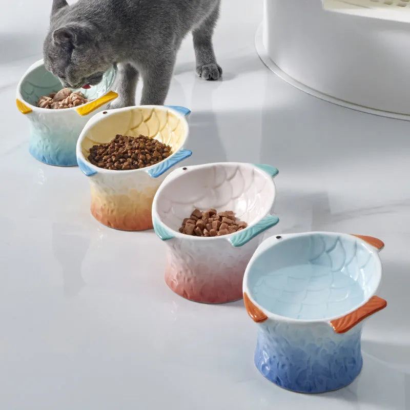 Blue fish-shaped ceramic cat bowl with 15-degree tilt angle on a wooden floor.