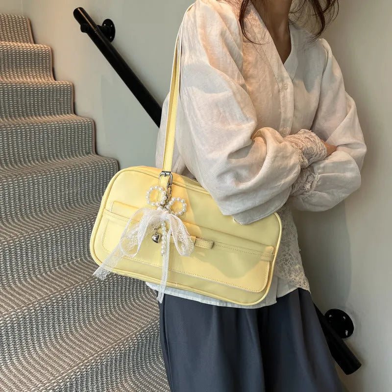 A horizontal square PU flap handbag in a solid colour with double-joint shoulder straps and optional pearl bow ornament.