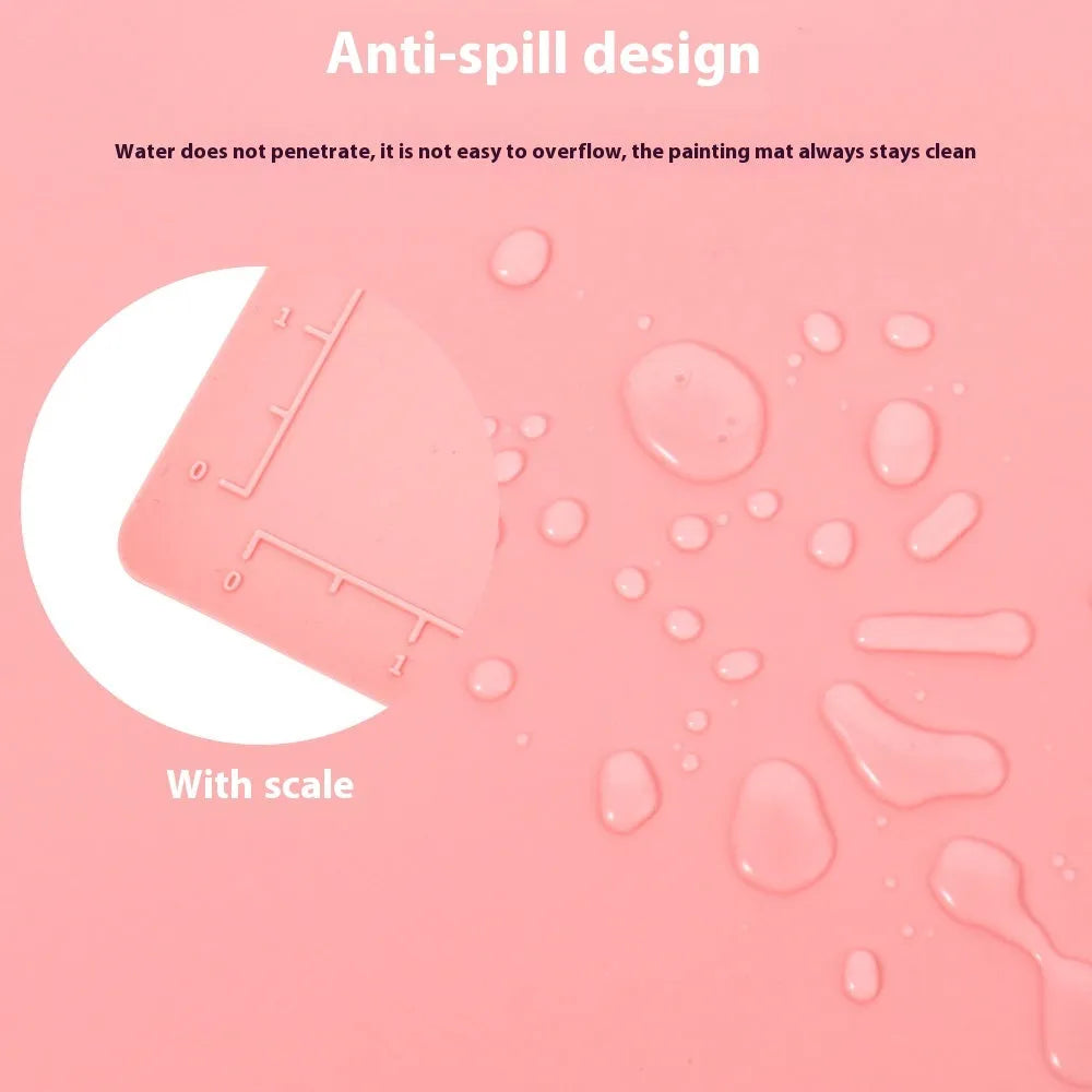 Light blue silicone painting mat with two bowl depressions for water and brushes, placed on a wooden table.