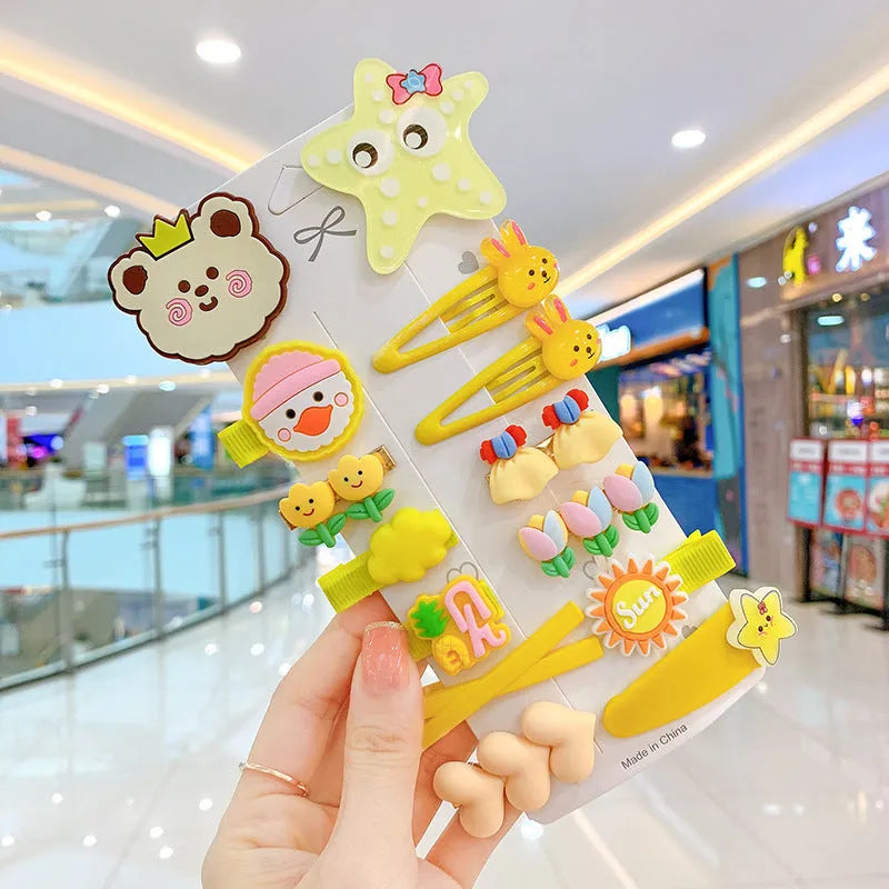 14-piece set of colourful toddler hair clips with candy, fruit, rainbow, and butterfly designs on a white background.