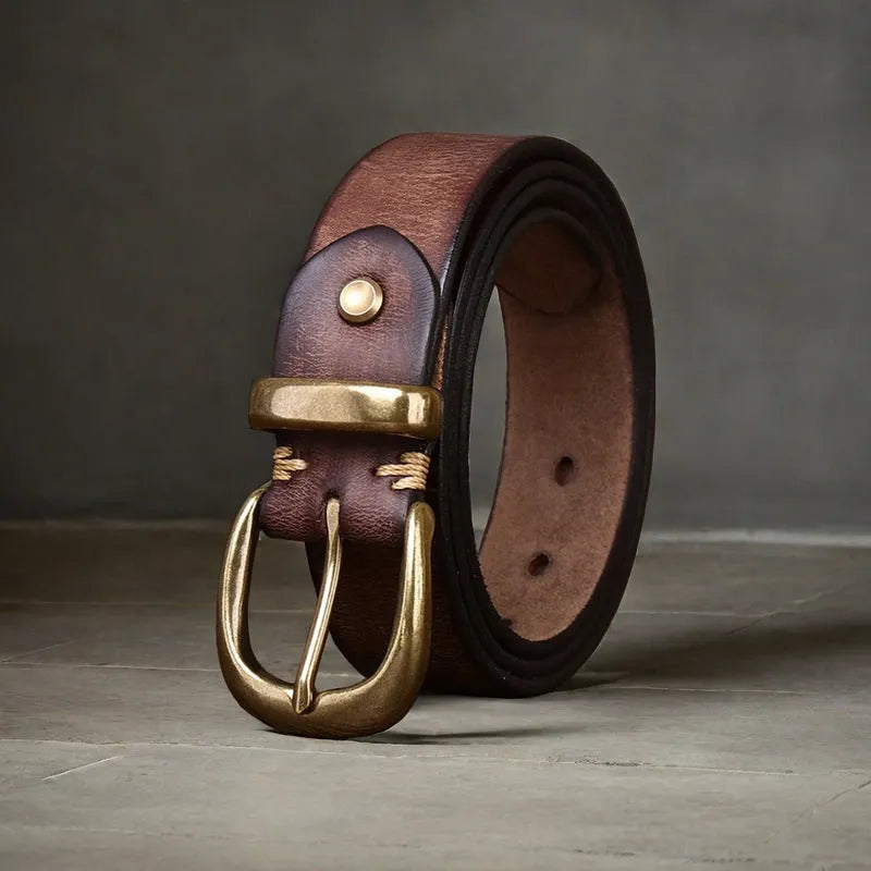 Men's brown leather belt with copper pin buckle on a pair of jeans.