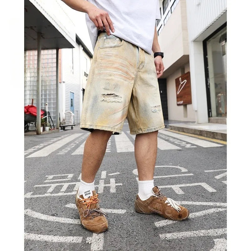 Light blue ripped denim shorts for men on a mid-thigh model, showing straight-leg cut and distressed details.