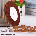 Roll of narrow gold polyester ribbon next to a wrapped gift box.