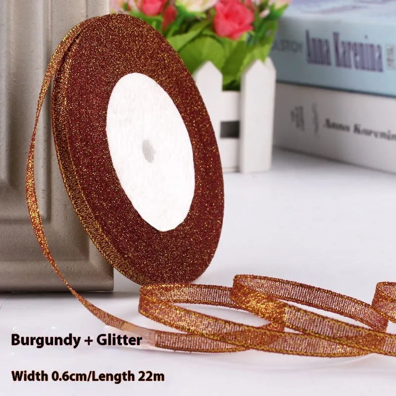 Roll of narrow gold polyester ribbon next to a wrapped gift box.
