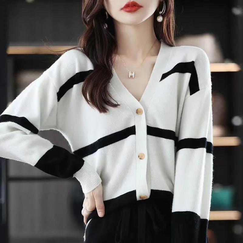 A woman wearing a slim-fit black and white striped V-neck knitted cardigan.