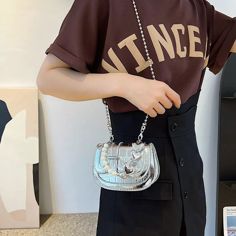 Silver laser pearl finish women's crossbody mini saddle tote bag with single shoulder strap.