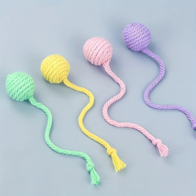 Green cat toy ball with attached rope on a wooden floor, shown next to a yellow 3cm size version.