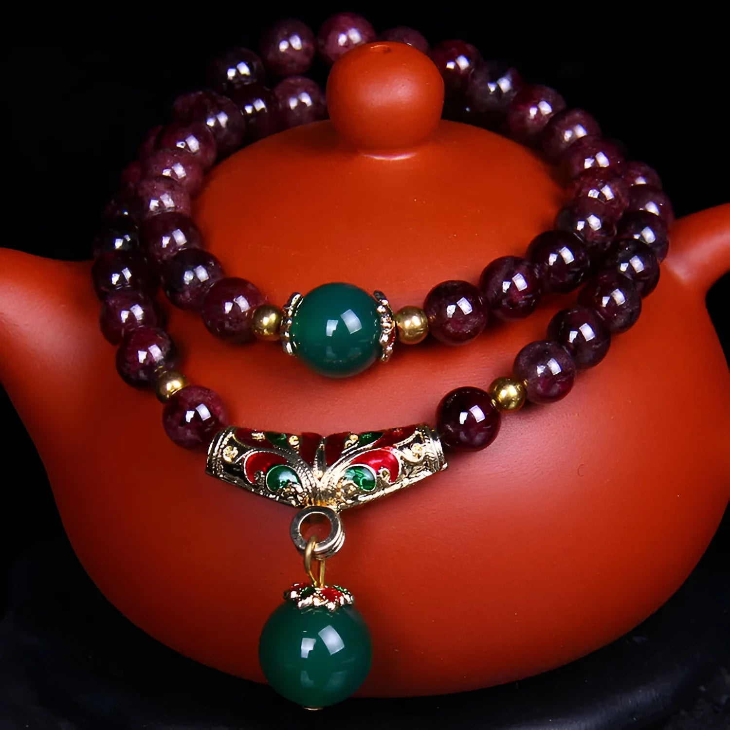 Natural deep red garnet bead bracelet with a golden toad charm, shown in 7mm size on a wrist.