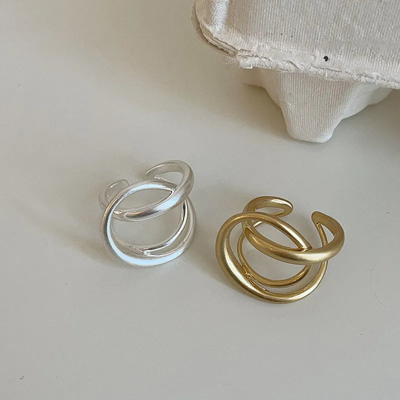 Geometric open ring for women with a three-dimensional interlaced design in matte metal.
