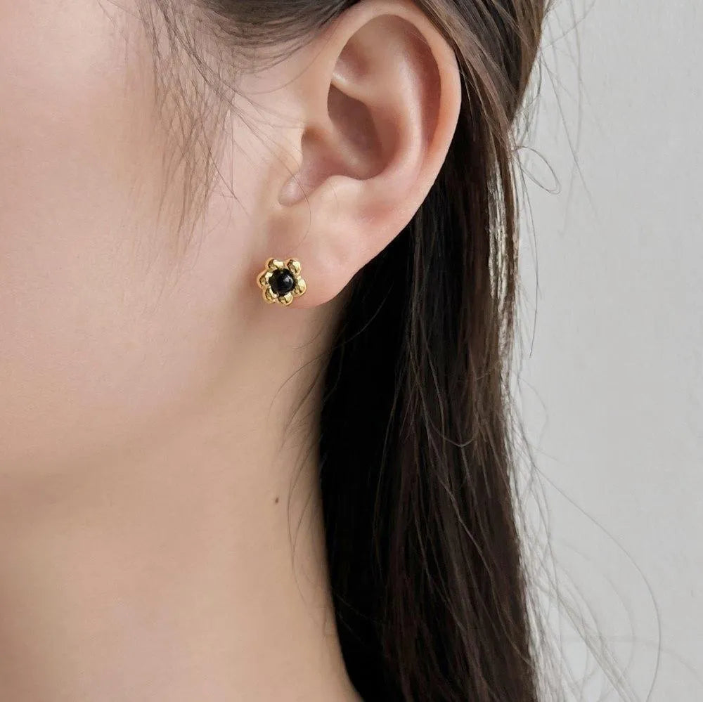 S925 sterling silver black agate flower ear studs in gold colour on a woman's ear