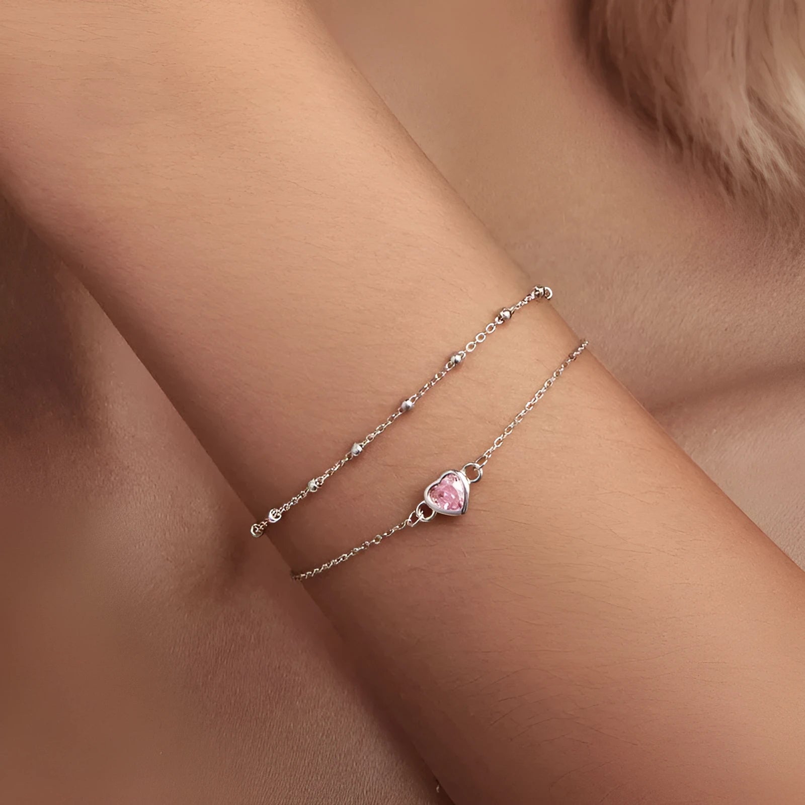 Women's sterling silver bracelet with a small heart-shaped charm on an adjustable chain.