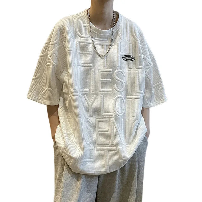 Men's grey loose-fit t-shirt with a raised black three-dimensional letter print on the front.