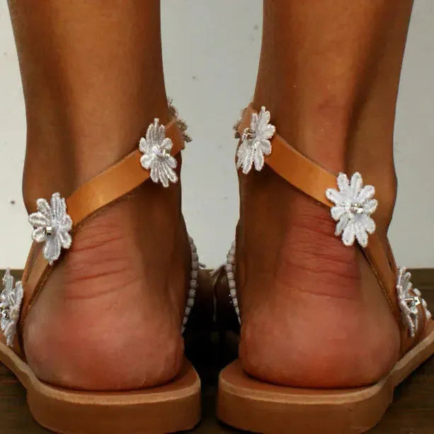 Brown women's flat sandals with flower detail and herringbone toe pattern on rubber sole.