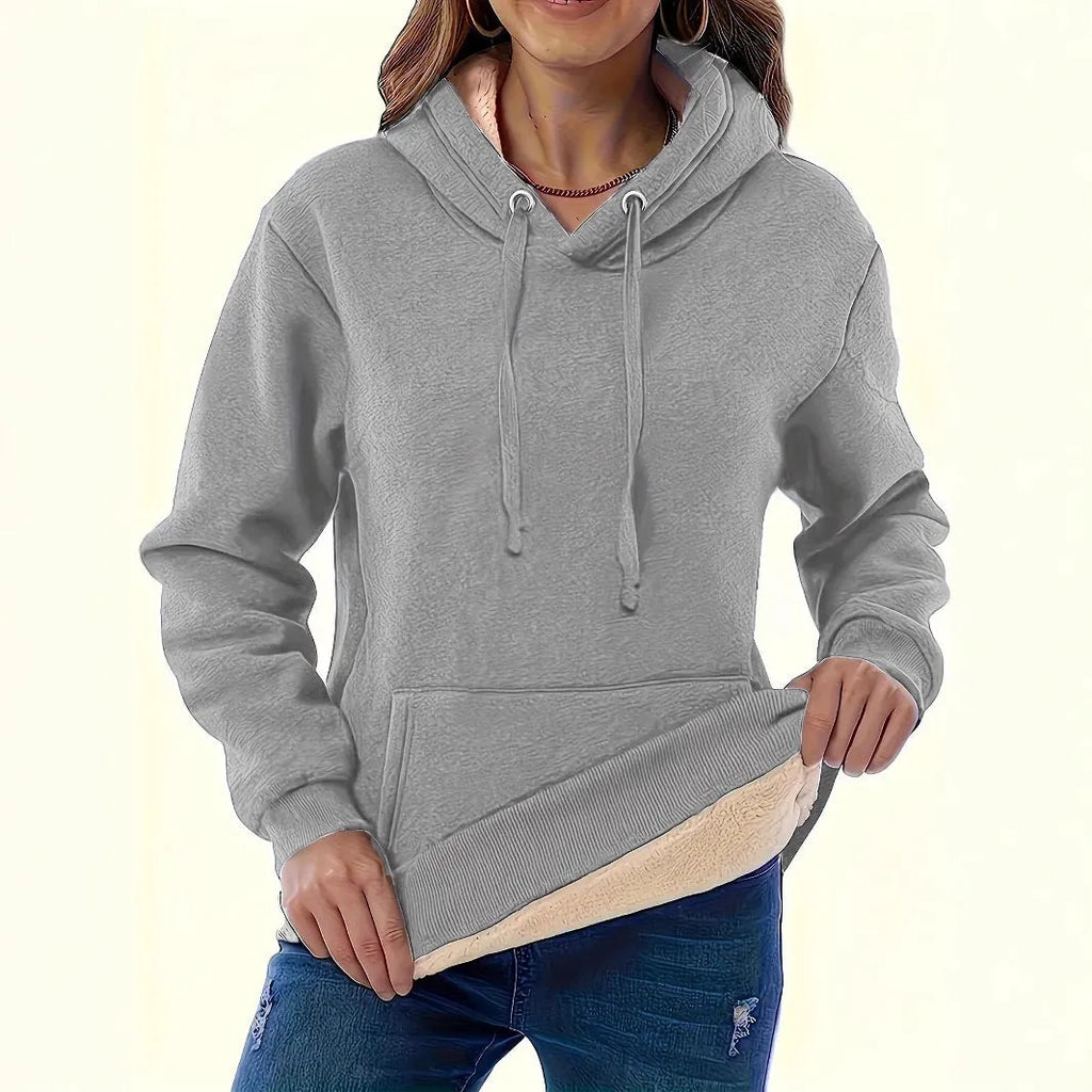 Woman wearing a thick grey hooded sweater with a 3D pattern and front pockets