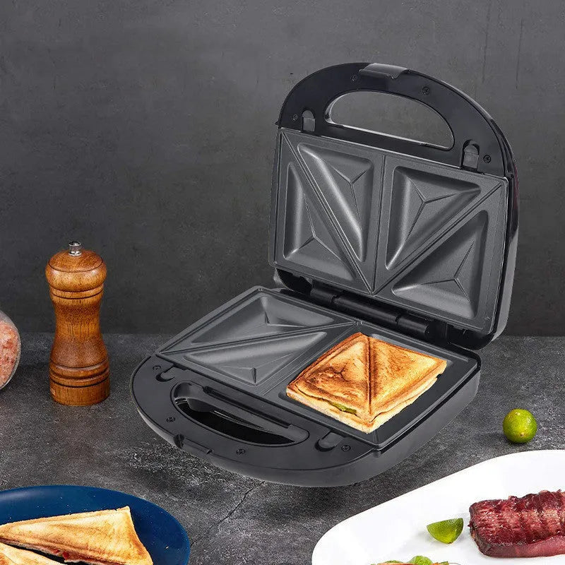 Black double-sided electric sandwich pan with stainless steel lid on a kitchen counter