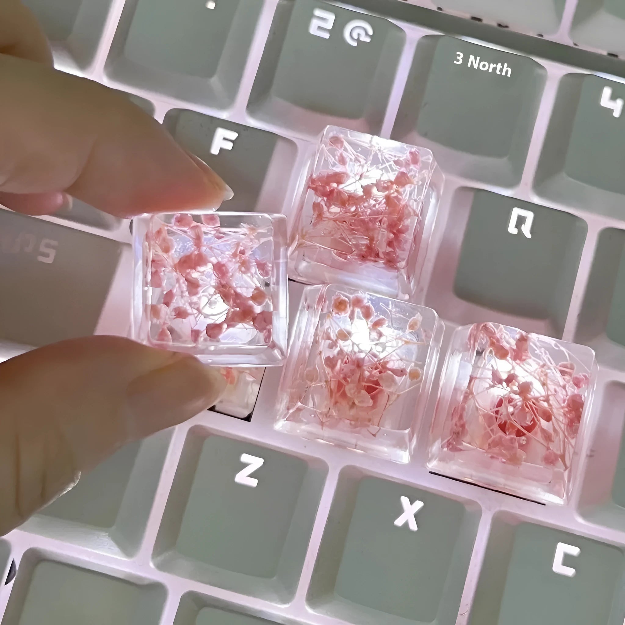 Transparent resin mechanical keyboard keycap with starry sky design in green, pink, red, violet colours.