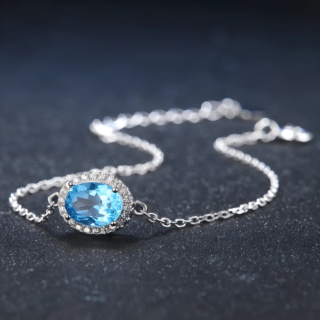 Women's 925 sterling silver and blue topaz four-piece jewellery set with geometric design, showing earrings, ring, necklace, and pendant.
