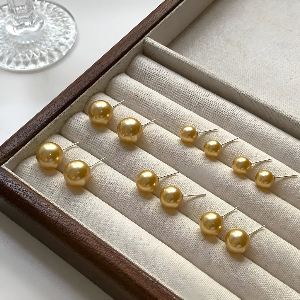 Large pearl stud earrings in geometric shape with eight awn star detail and pearl accents on silver background