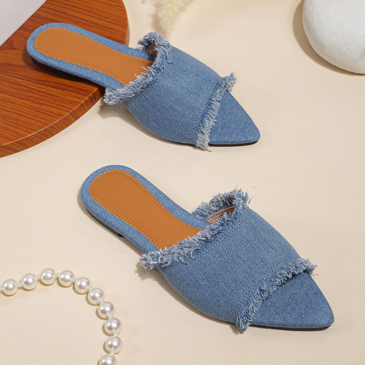 Women's flat denim slippers with a tassel detail, shown in apricot colour.