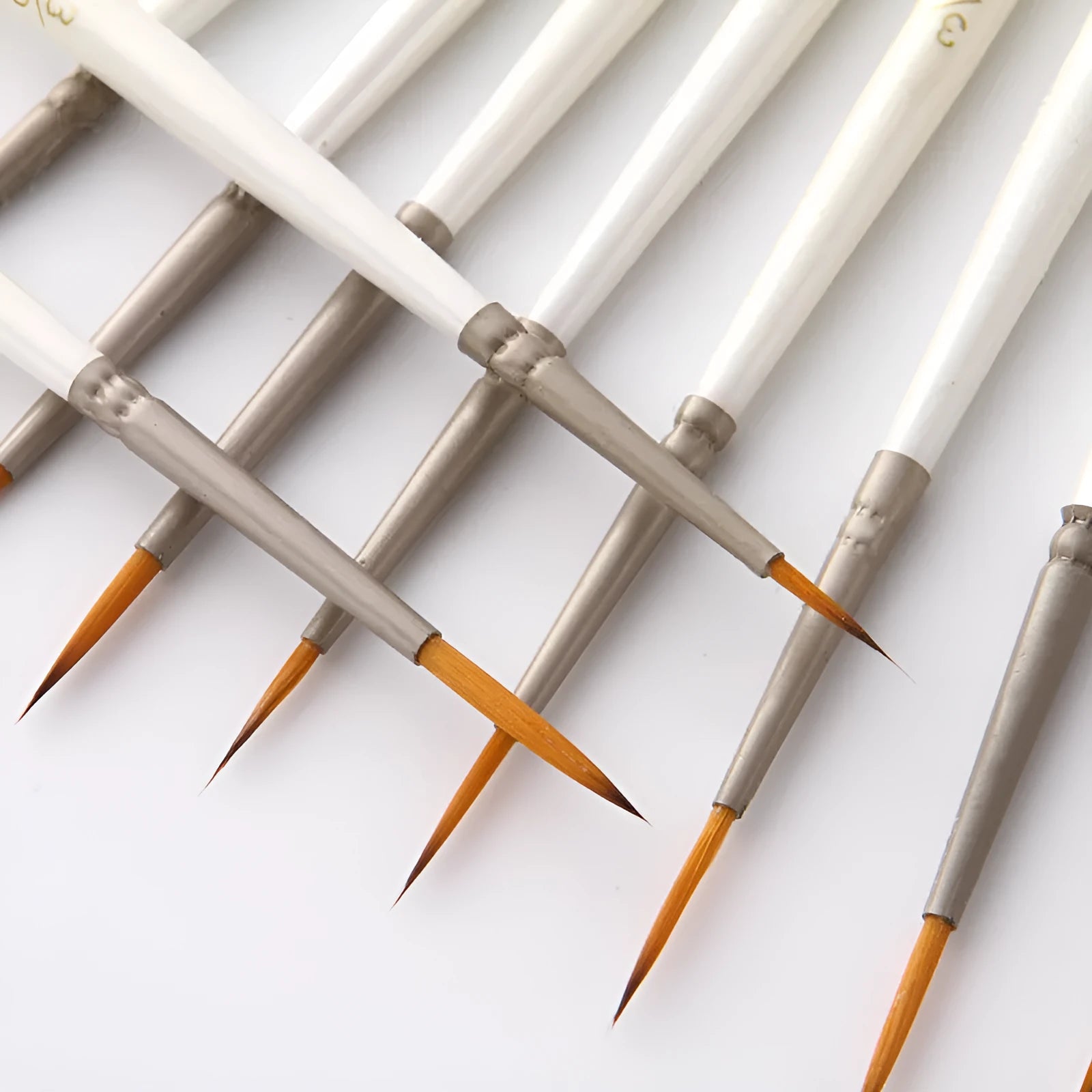 12 pearl white handled artist brushes with nylon wool bristles, stored upright in a solid wood pen holder.