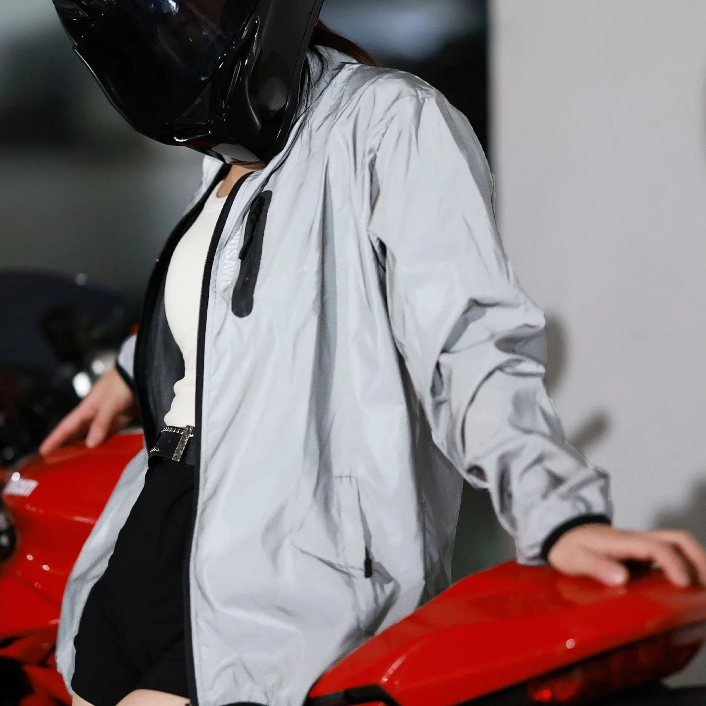 Silver coloured waterproof polyester long sleeved coat with hood on a hanger.
