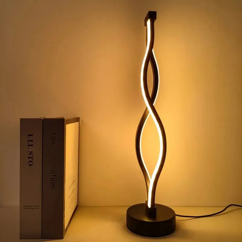 Black aluminium desk lamp on a table showing its three-colour dimming button and touch panel.