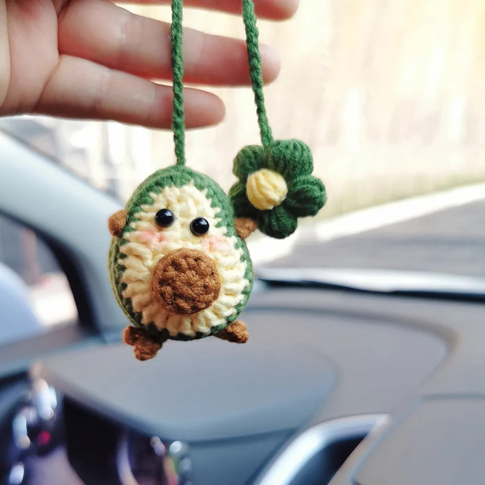 Handmade crocheted wool car pendant shaped like a cartoon avocado with a rainbow flower decoration.