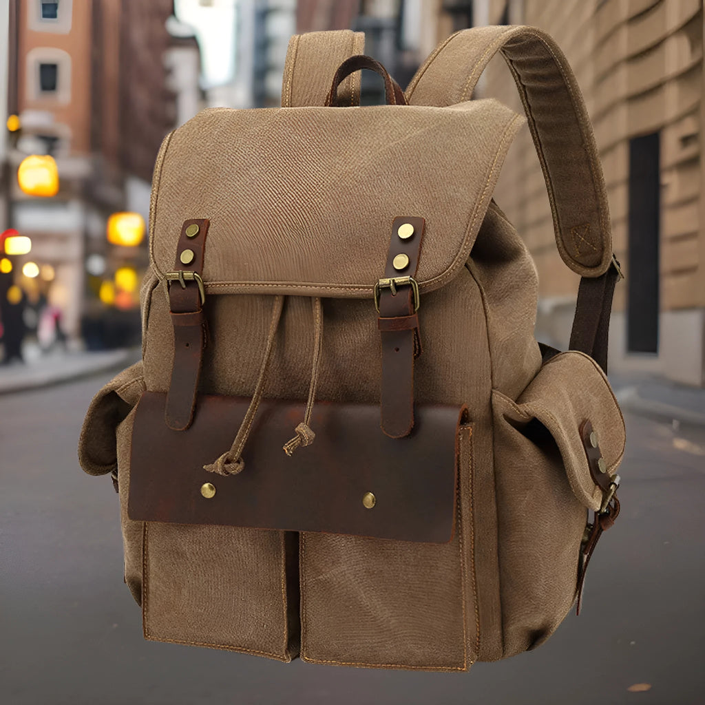 Retro military green canvas backpack with antique bronze hardware, shown with a laptop.