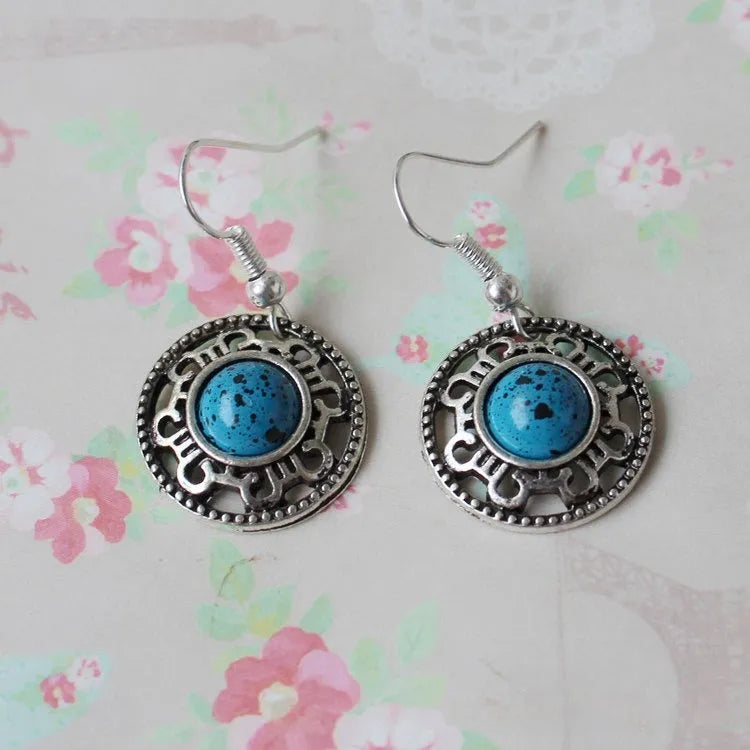 Handmade geometric flower disk earrings in Tibetan silver and turquoise, showing totem patterns.