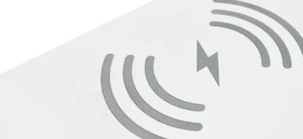 White 3-in-1 LED night light with wireless charger and alarm clock on a bedside table, 23.8cm tall
