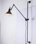 Black rotating rocker arm eye protection wall lamp with plug and Nordic iron lampshade showing warm bulb