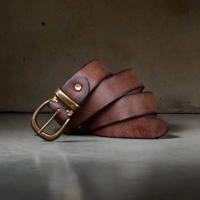 Men's brown leather belt with copper pin buckle on a pair of jeans.