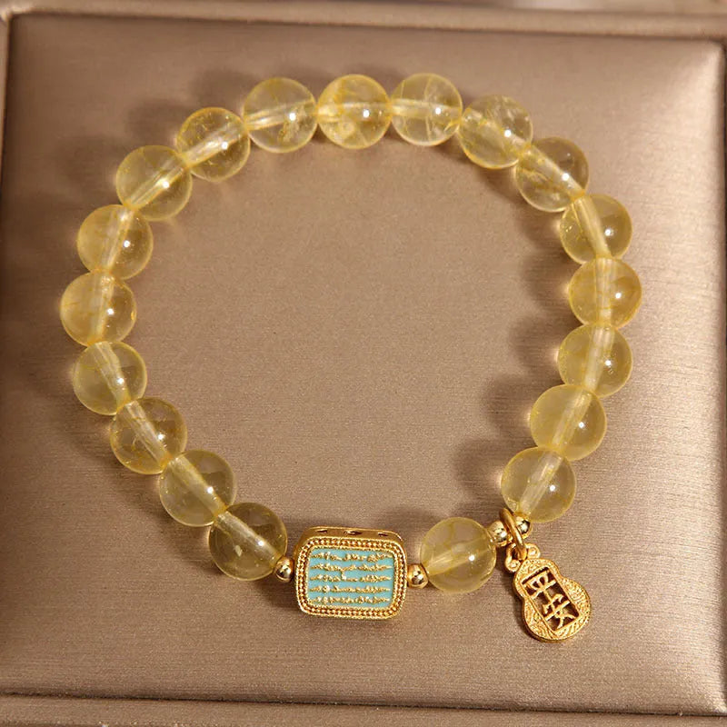 Women's bracelet with yellow citrine stones and sparkling rhinestone details on a white background.