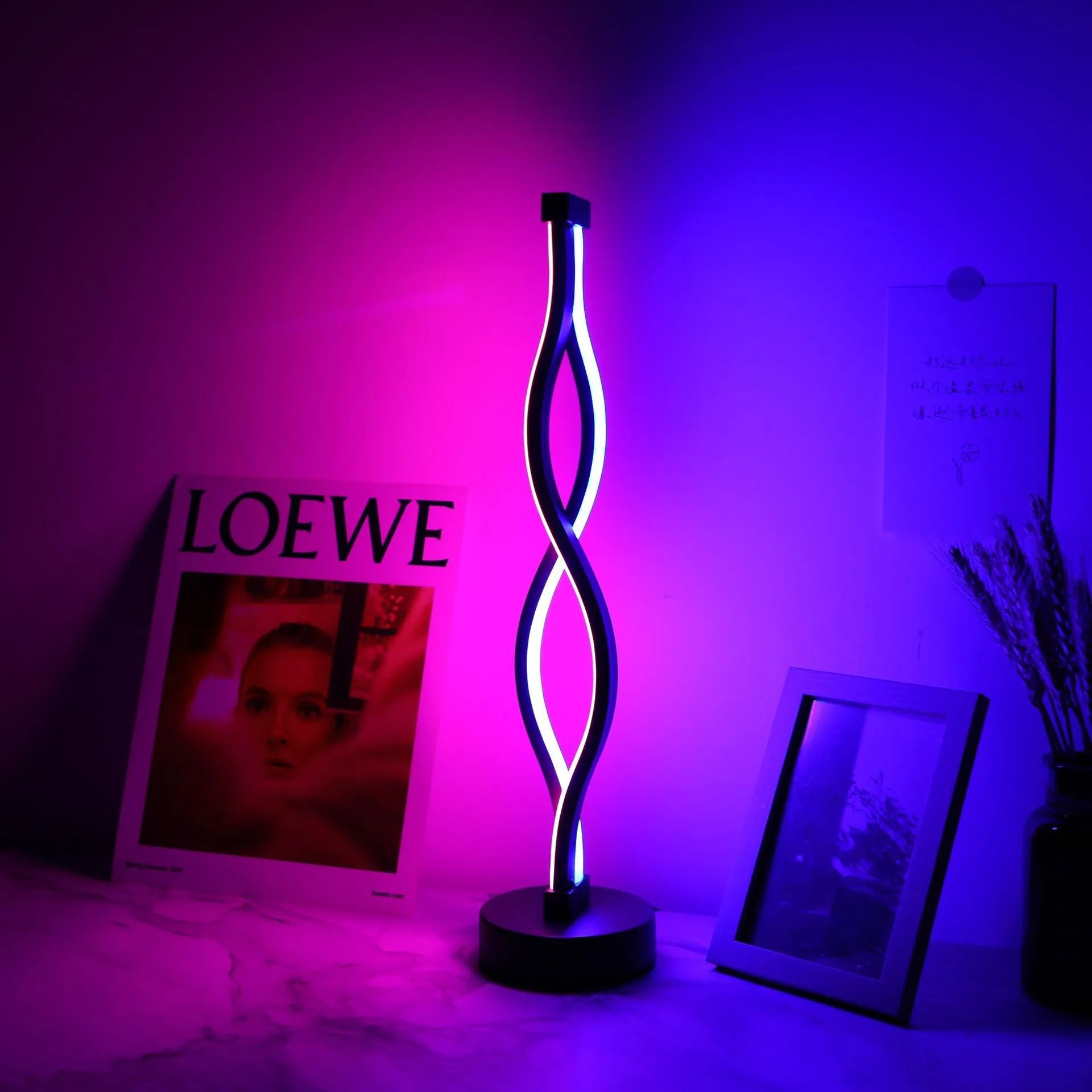 Black aluminium desk lamp on a table showing its three-colour dimming button and touch panel.