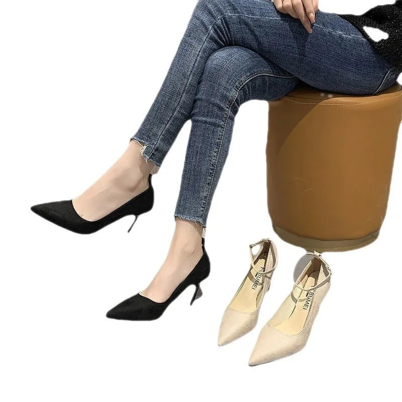 Women's black stiletto pump shoe with a decorative buckle and skull pattern on the toe.