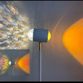 Sunset red floor lamp projecting a water wave light pattern onto a wall in a modern room.