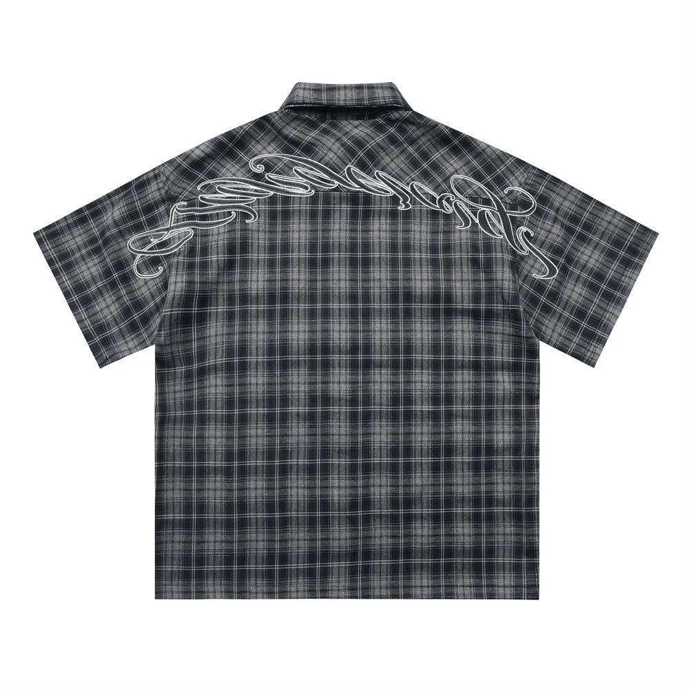 Men's black and brown plaid short sleeve shirt with embroidered lettering and lapel collar.
