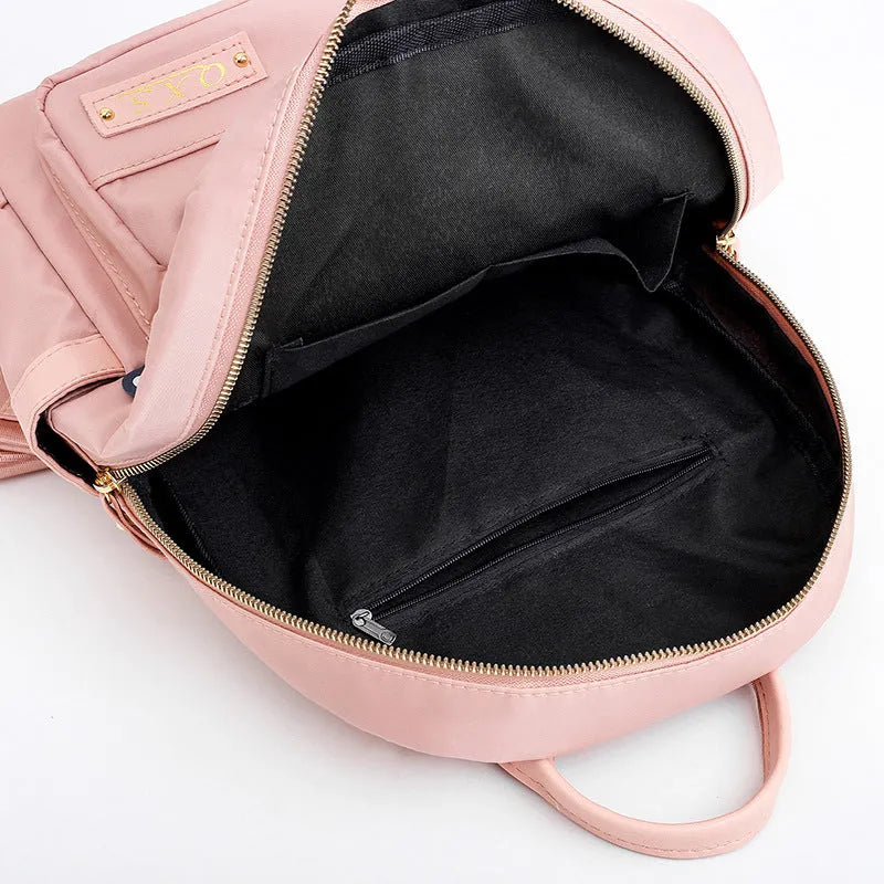 Black or pink women's casual nylon backpack with soft handle, showing internal zipper pockets and double shoulder straps.