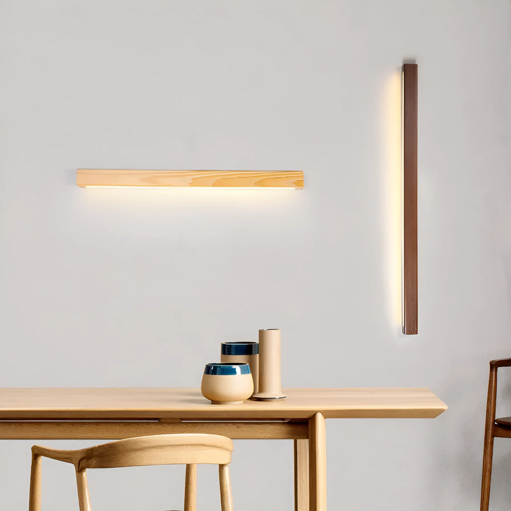Walnut-coloured linear wood and acrylic strip wall lamp mounted on a light wall.