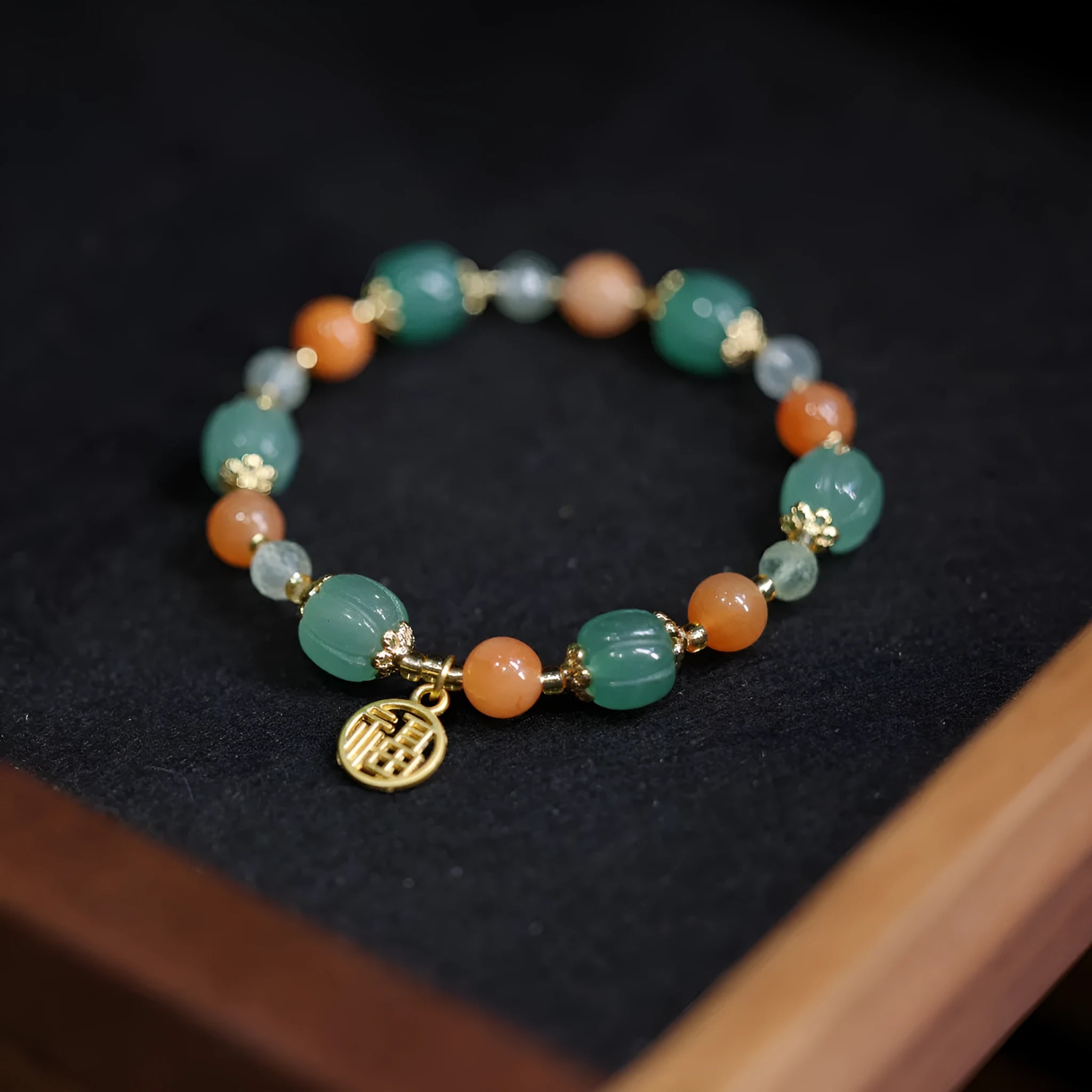 Jinsi Jade Duobao pumpkin bracelet with Prehnite bead on a flat surface, showing carved pumpkin bead and spacer beads