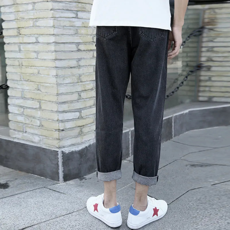 Man wearing black loose fit straight leg cotton jeans, showcasing the high-rise harem style and light straight leg opening.