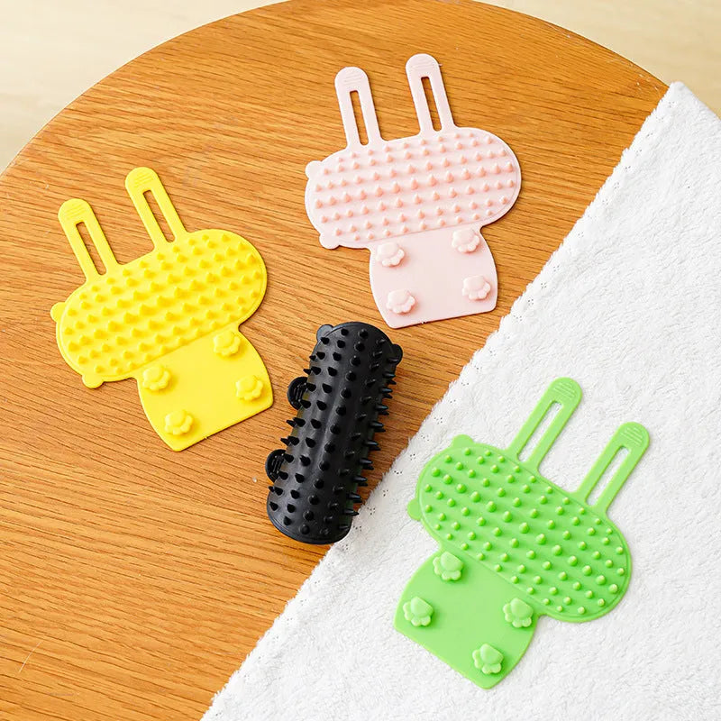 Silicone cat grooming brush with comb teeth mounted on table leg for scratching and hair removal
