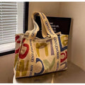 Large canvas tote bag with printed design showing black letters, available in multiple pattern options