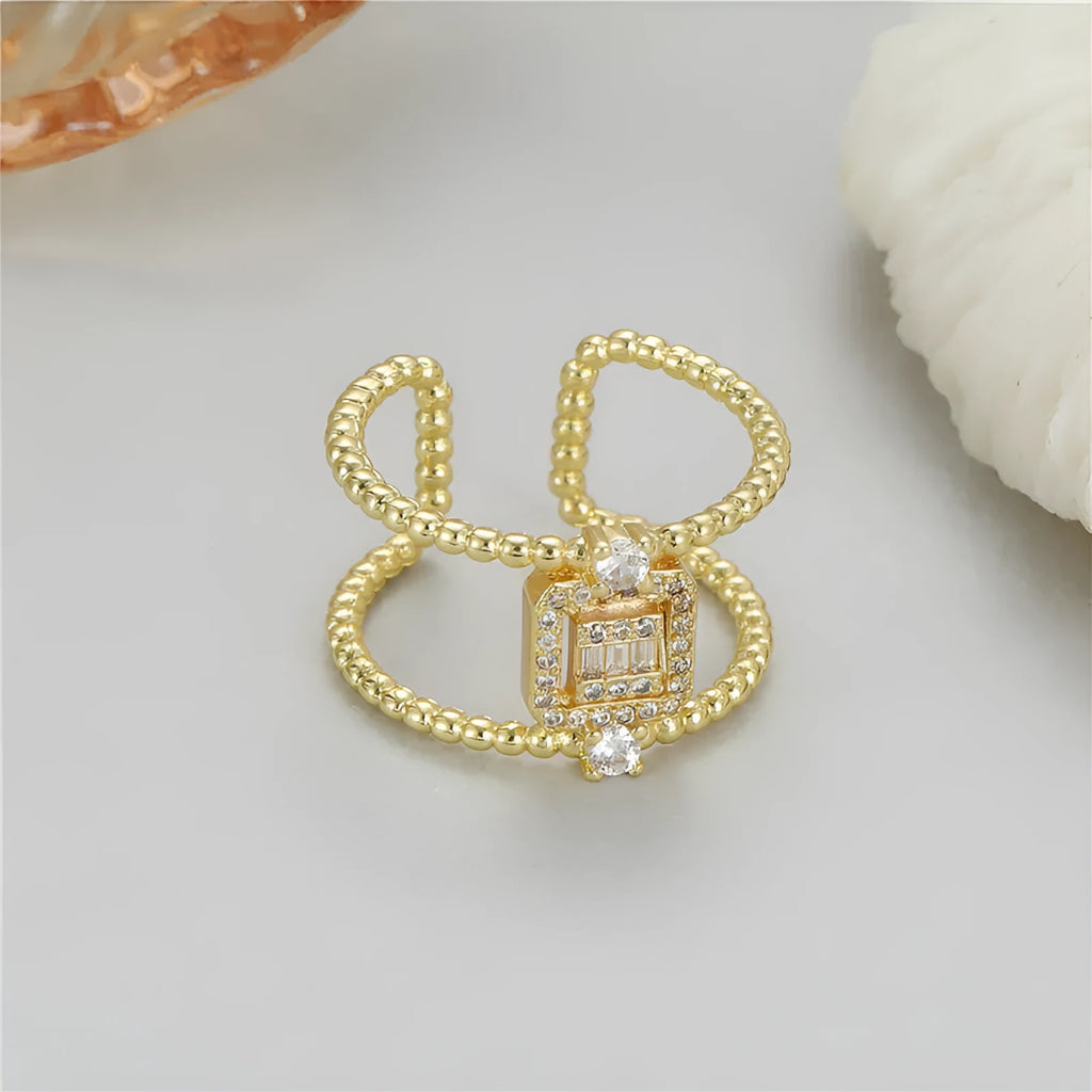 Gold-plated copper adjustable open ring with an asymmetric U-shaped design on a flat surface.