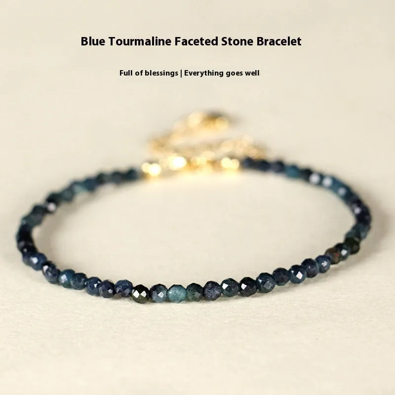 Close-up of a women's bracelet with small blue tourmaline beads and spacer beads on a wrist.