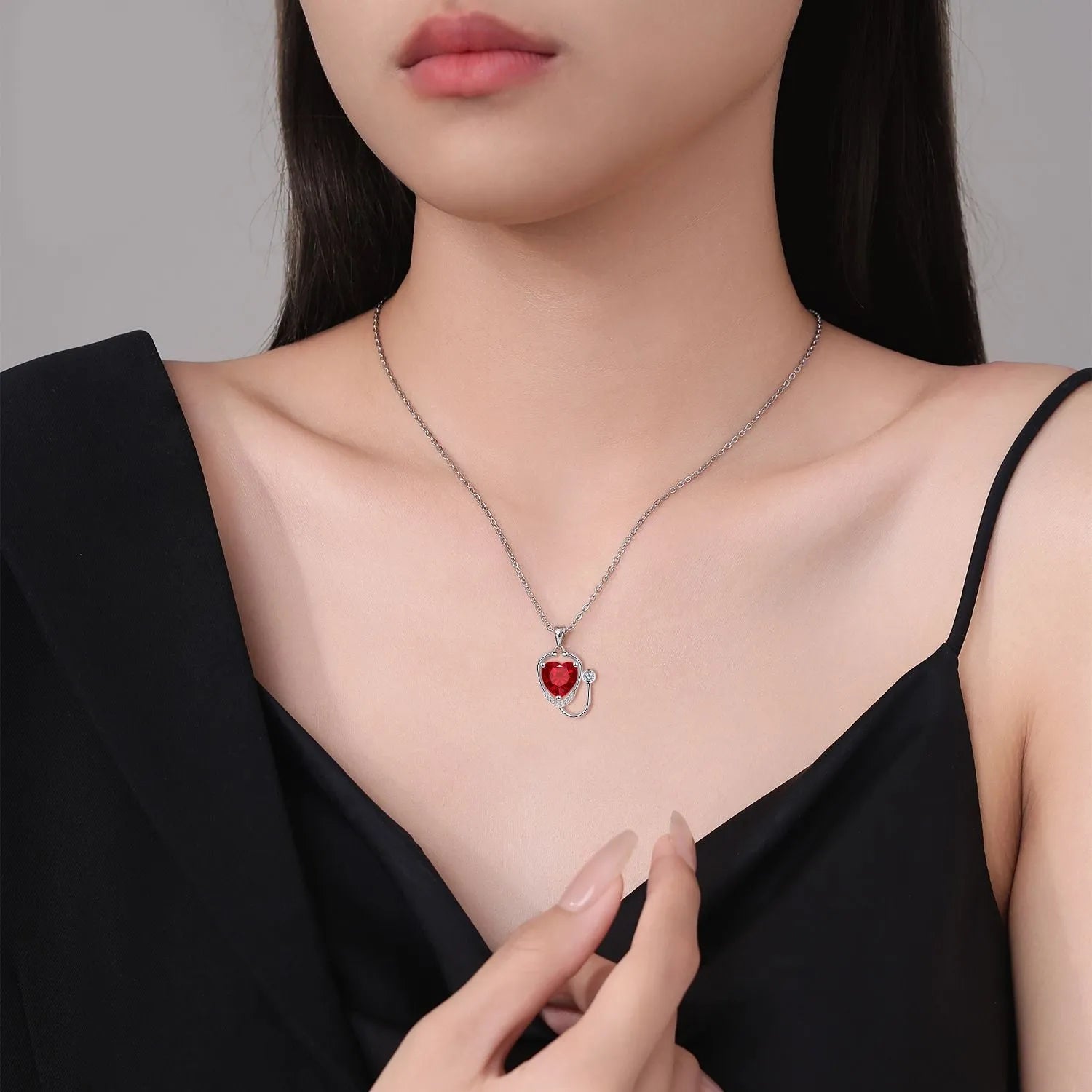 Red diamond women's necklace with a stethoscope, wings, and cross pendant on an adjustable chain.