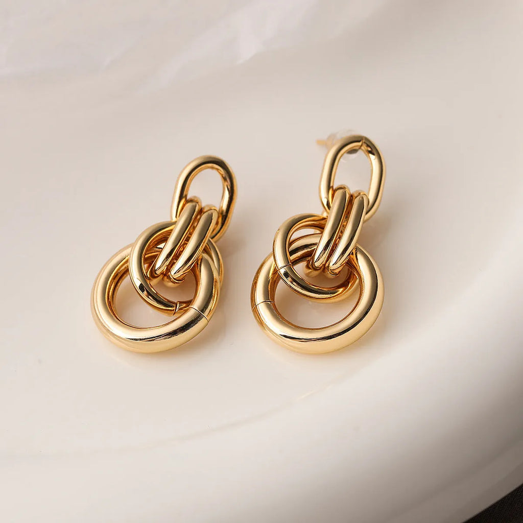 Gold geometric copper earrings with irregular asymmetric design on display