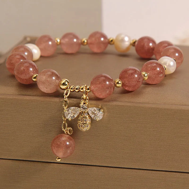 Women's bracelet with three freshwater pearls, a pink strawberry quartz charm, and sparkling zircon stones on an alloy chain.