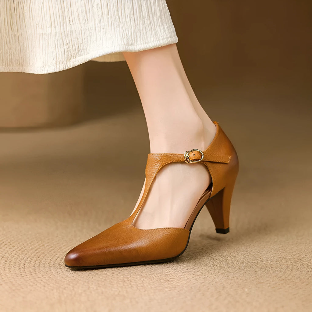 Brown retro women's T-strap sandals with a closed round toe and a short stout heel on a wooden background.